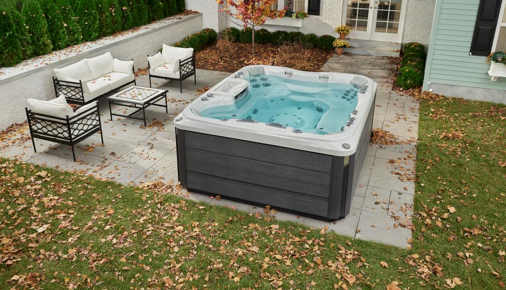 A hot tub surrounded with yellow leaves on a patio
