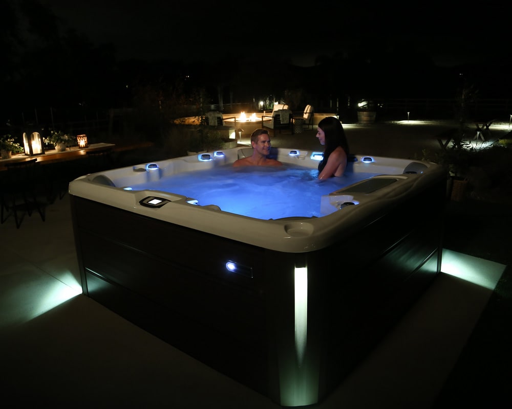 Couple enjoying illuminated hot tub at night: interior & exterior LED lights