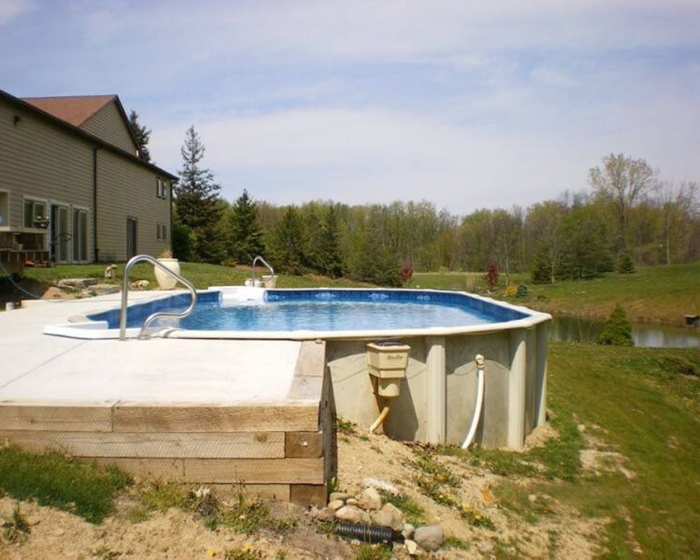 Doughboy Above-ground oval pool with clean blue water, white ladders, and a house in a sunny suburban backyard