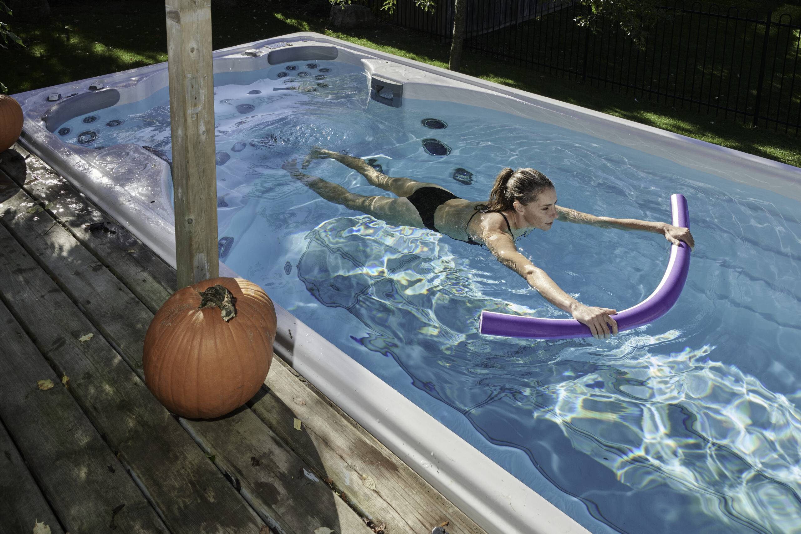 A woman exercising with a pool noodle in her SwimLife Swim Spa